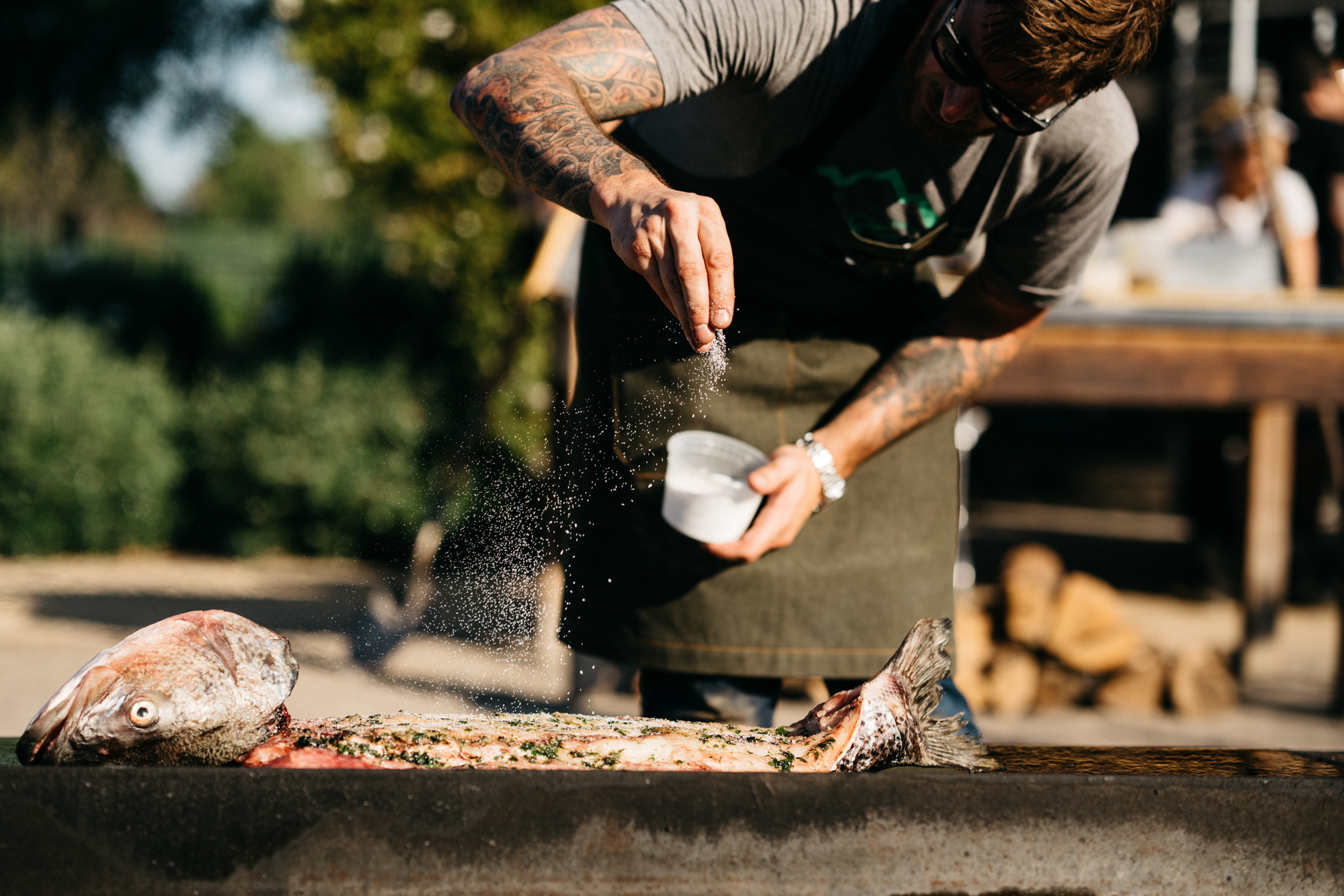 Chef sprinkling salt over fish at Farmstead Live Fire