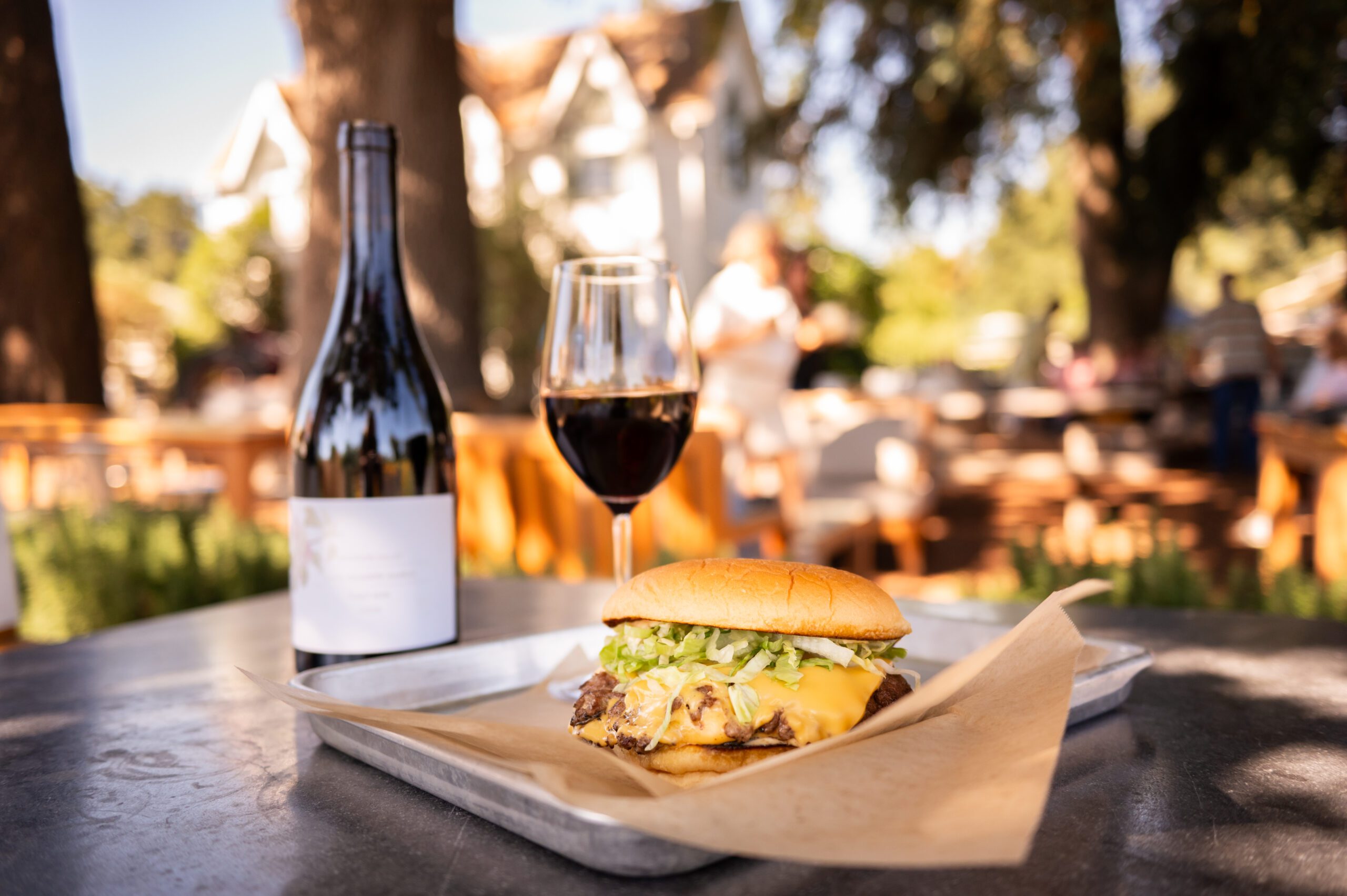 Farmstead Smashburger on a tray next to a bottle and glass of wine